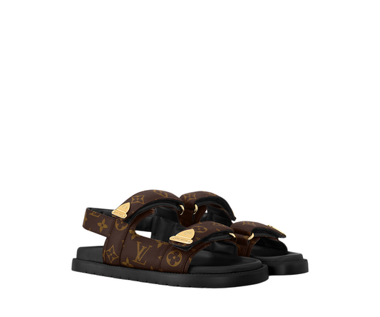 Front view of Louis Vuitton LV Sunset Comfort Sandals in brown Monogram canvas featuring adjustable straps and gold hardware on a white background.